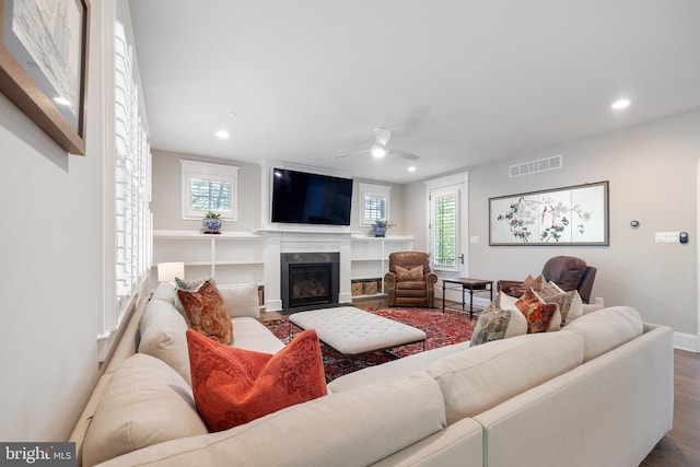 living area with a ceiling fan, recessed lighting, a fireplace with flush hearth, wood finished floors, and visible vents