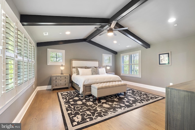 bedroom featuring baseboards, lofted ceiling with beams, wood finished floors, and multiple windows