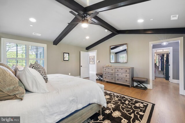 bedroom with visible vents, lofted ceiling with beams, wood finished floors, and multiple windows