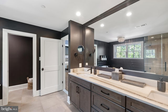 full bath featuring double vanity, visible vents, tile patterned flooring, a sink, and baseboards
