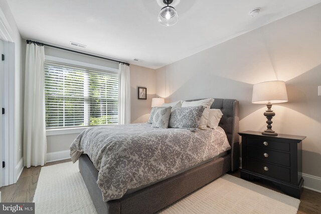 bedroom featuring baseboards, wood finished floors, and visible vents