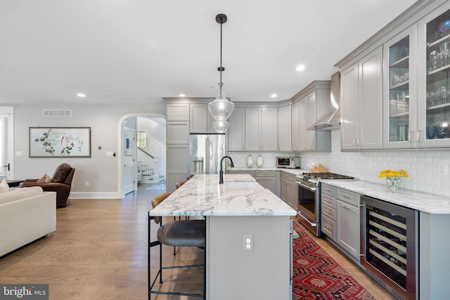 kitchen featuring visible vents, wall chimney exhaust hood, high end appliances, wine cooler, and gray cabinetry