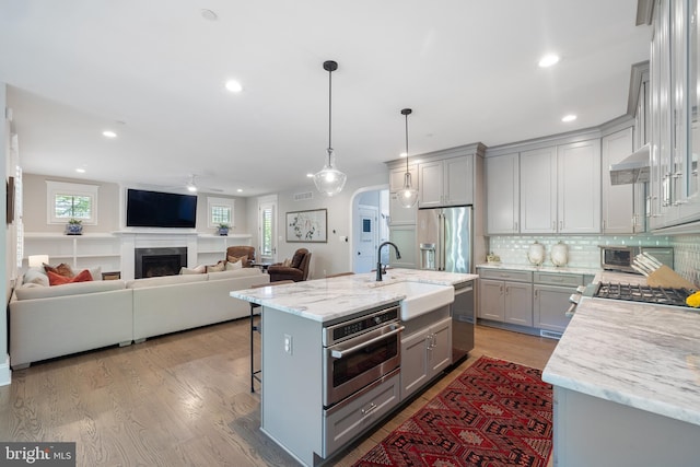 kitchen with ceiling fan, a sink, arched walkways, stainless steel appliances, and gray cabinetry