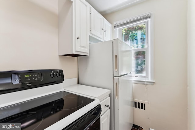 kitchen featuring light countertops, electric range oven, and white cabinetry
