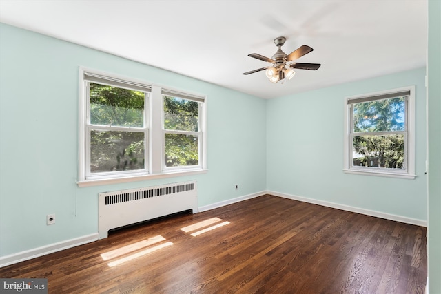 unfurnished room featuring radiator, baseboards, dark wood-style flooring, and ceiling fan
