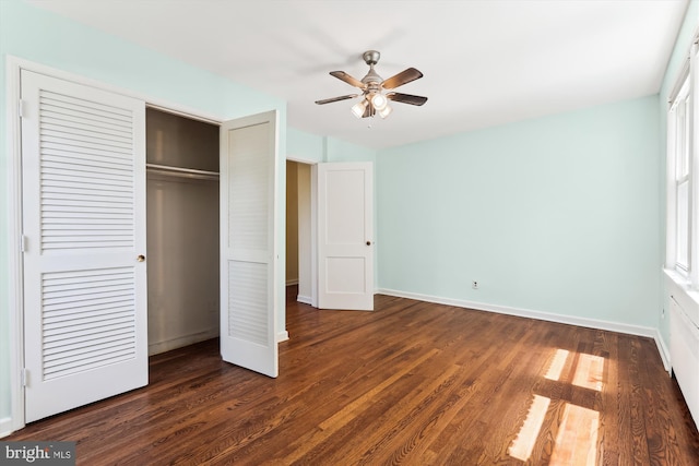 unfurnished bedroom featuring baseboards, a ceiling fan, a closet, and dark wood-style floors