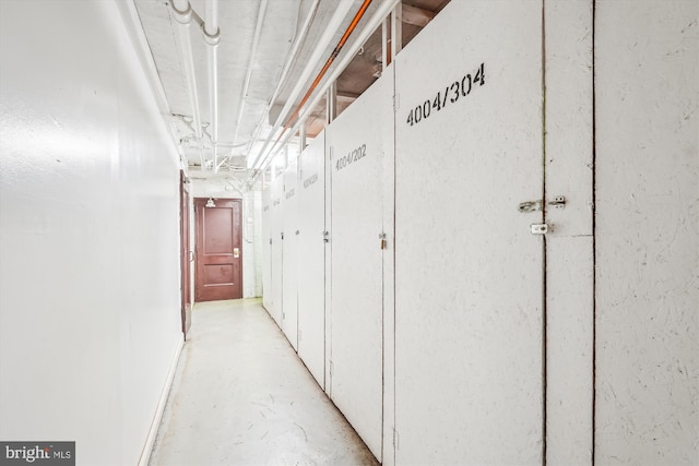 corridor featuring baseboards and concrete floors