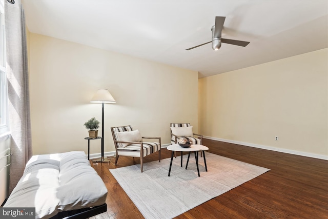 living area featuring baseboards, a ceiling fan, and wood finished floors