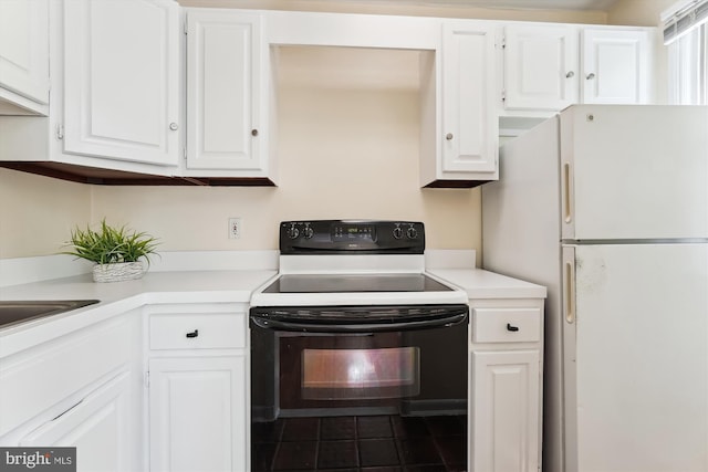 kitchen featuring freestanding refrigerator, white cabinetry, black electric range, and light countertops