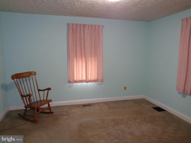 unfurnished room with a textured ceiling, visible vents, and carpet floors
