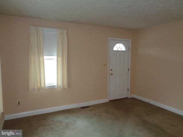 entrance foyer featuring a textured ceiling, visible vents, carpet floors, and baseboards