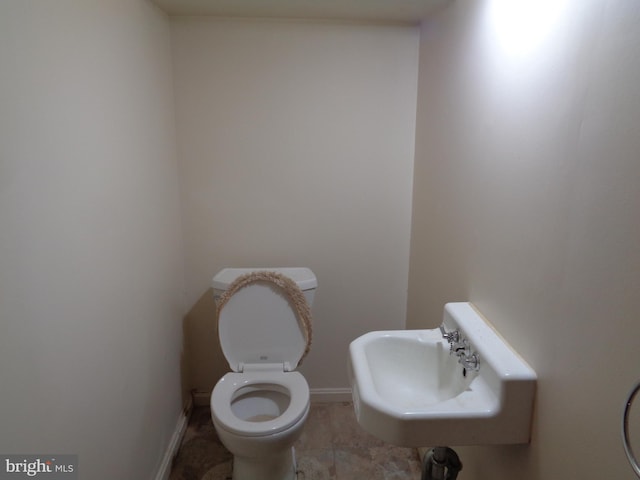 bathroom featuring toilet, a sink, and baseboards
