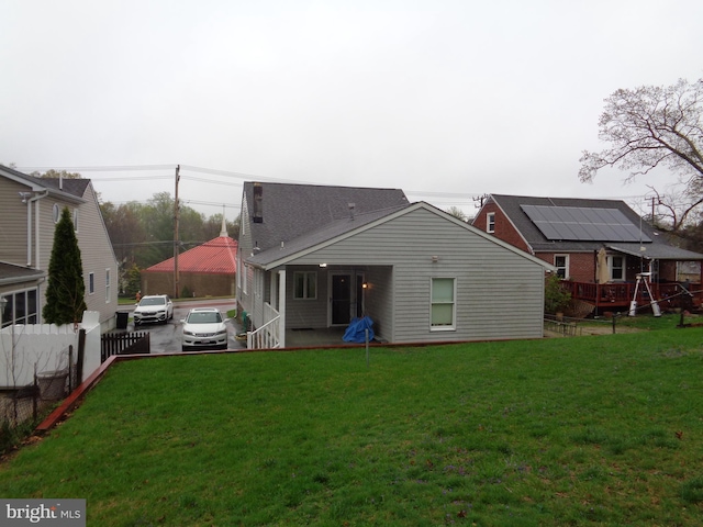 rear view of house featuring a yard and fence