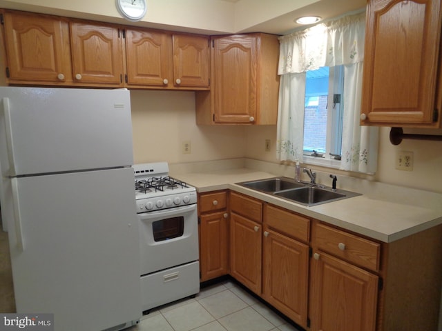 kitchen with white appliances, brown cabinetry, light countertops, a sink, and light tile patterned flooring