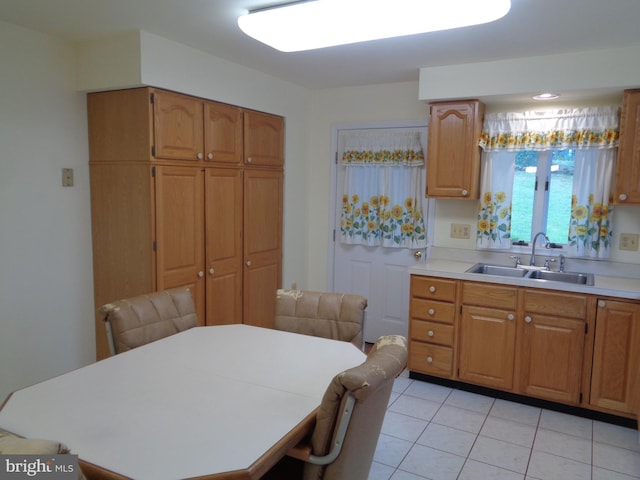kitchen with light tile patterned floors, brown cabinets, light countertops, and a sink