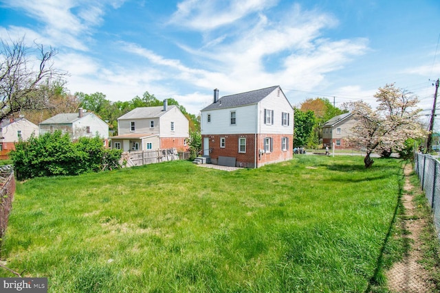 back of property featuring brick siding, a residential view, a lawn, and a fenced backyard
