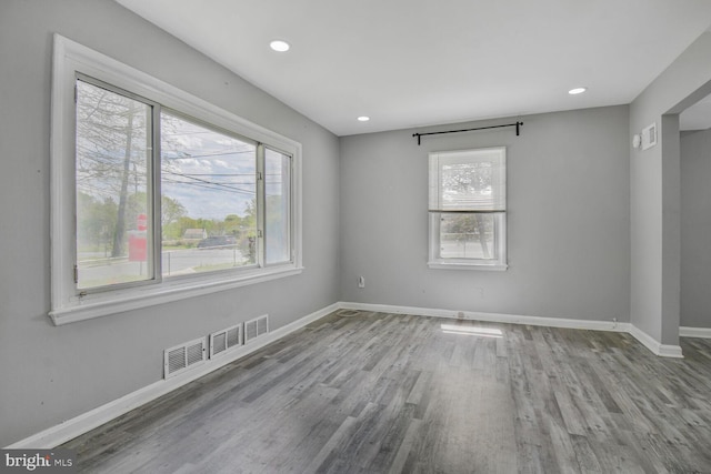unfurnished room featuring recessed lighting, wood finished floors, visible vents, and baseboards