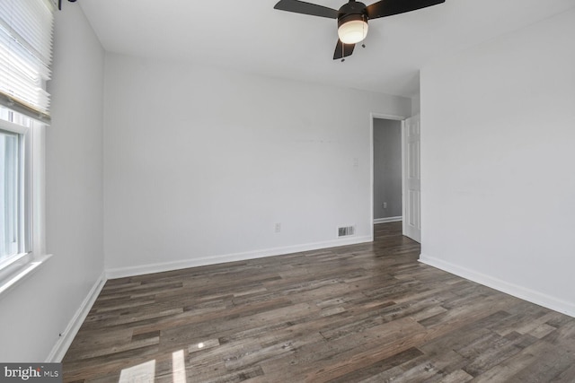 spare room with baseboards, visible vents, a ceiling fan, and dark wood-style floors