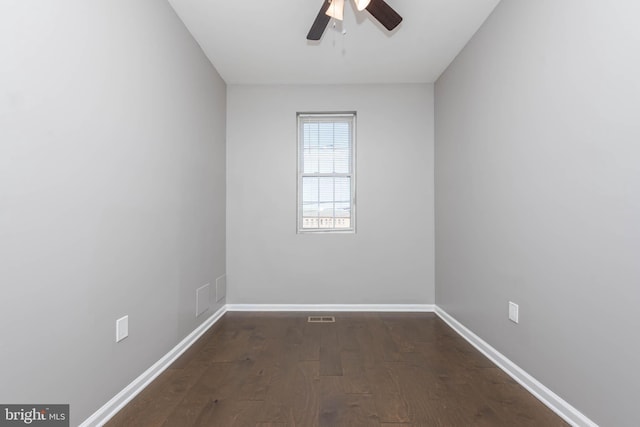 spare room featuring baseboards, a ceiling fan, and dark wood finished floors