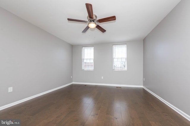 empty room featuring ceiling fan, baseboards, and dark wood-style flooring