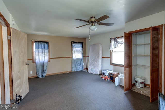 unfurnished bedroom featuring dark colored carpet, ceiling fan, and multiple windows