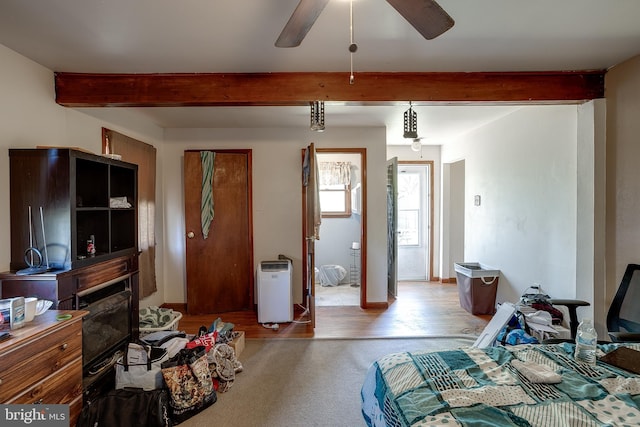 bedroom featuring a fireplace, beamed ceiling, and light wood finished floors