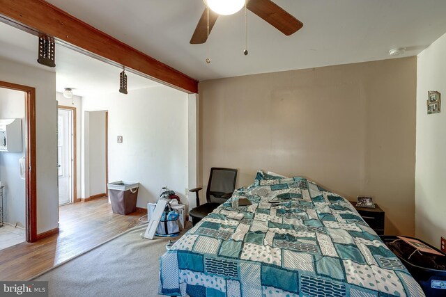 carpeted bedroom featuring beamed ceiling, a ceiling fan, and wood finished floors