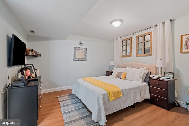 bedroom with visible vents, baseboards, and light wood finished floors