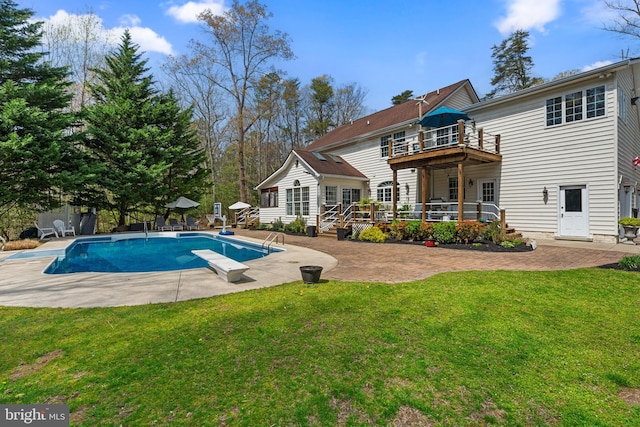 rear view of house featuring a fenced in pool, a patio, a wooden deck, and a lawn