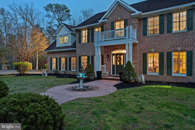 exterior space with brick siding, a yard, and a balcony