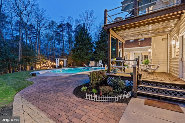 outdoor pool featuring a patio area, a wooden deck, and a lawn