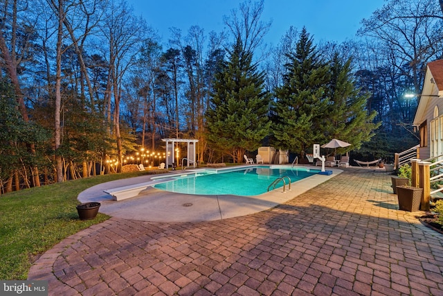 pool featuring a patio, a yard, and a diving board