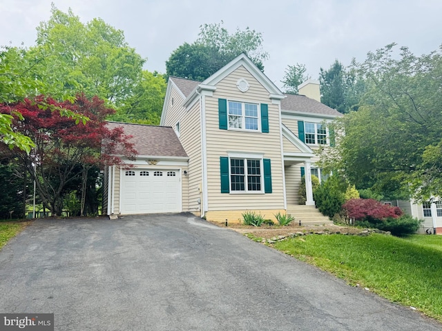 view of front of home with an attached garage, driveway, and a chimney