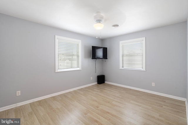 spare room with visible vents, ceiling fan, wood finished floors, and baseboards