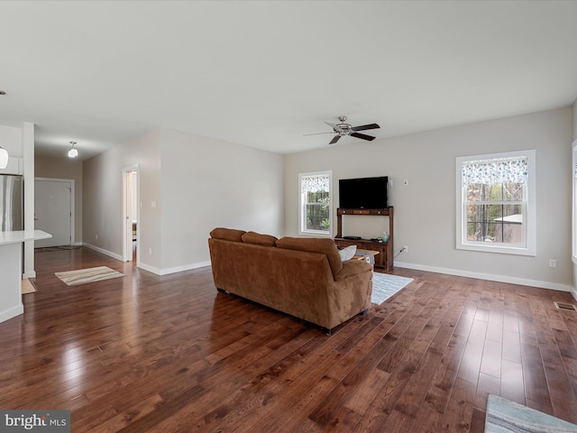 living room featuring visible vents, a ceiling fan, baseboards, and dark wood-type flooring