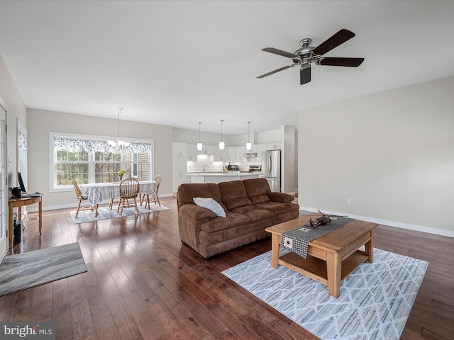 living area with baseboards, dark wood-style flooring, and ceiling fan with notable chandelier