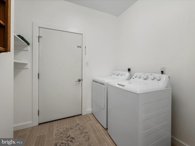 laundry area with wood tiled floor, baseboards, separate washer and dryer, and laundry area
