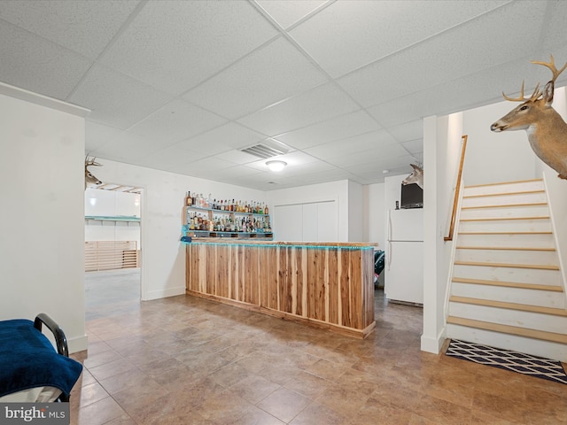 bar with a paneled ceiling, a dry bar, freestanding refrigerator, visible vents, and stairway