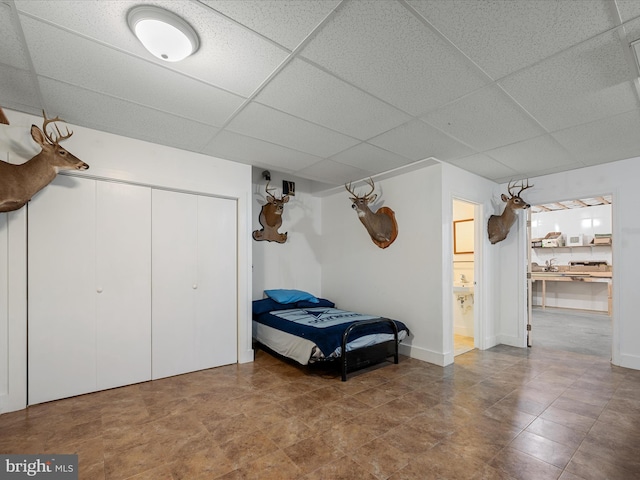 bedroom featuring a paneled ceiling, connected bathroom, and a closet
