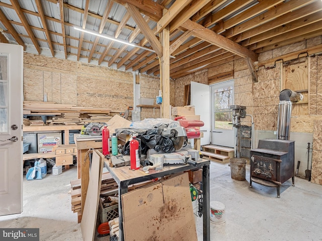 miscellaneous room featuring unfinished concrete floors, a wood stove, and a workshop area