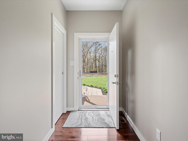 doorway with baseboards and wood finished floors