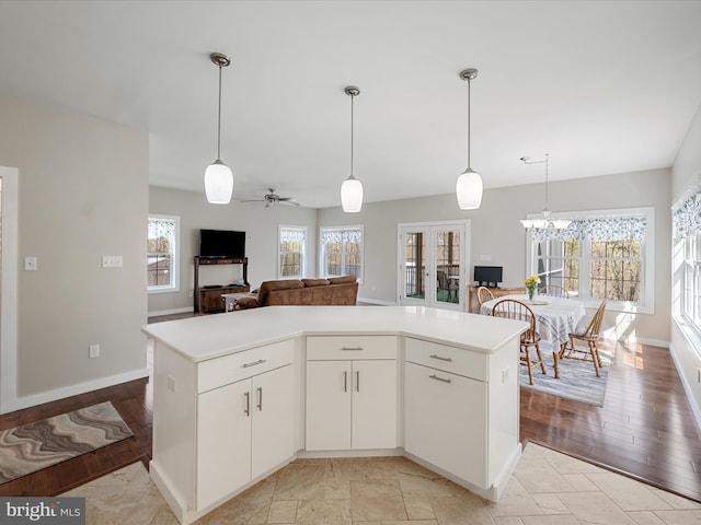 kitchen featuring ceiling fan with notable chandelier, light countertops, a wealth of natural light, and white cabinetry