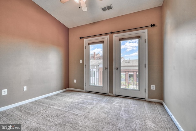 doorway featuring a ceiling fan, visible vents, carpet floors, baseboards, and lofted ceiling