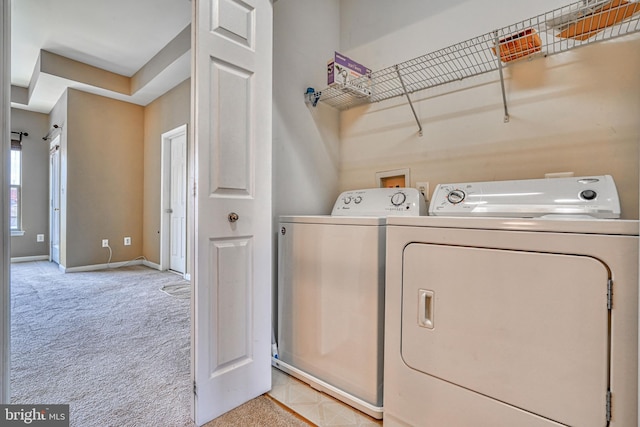 clothes washing area with separate washer and dryer, baseboards, laundry area, and light colored carpet
