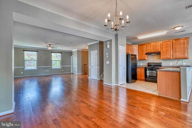 kitchen featuring ornamental molding, light wood-style flooring, under cabinet range hood, and black appliances