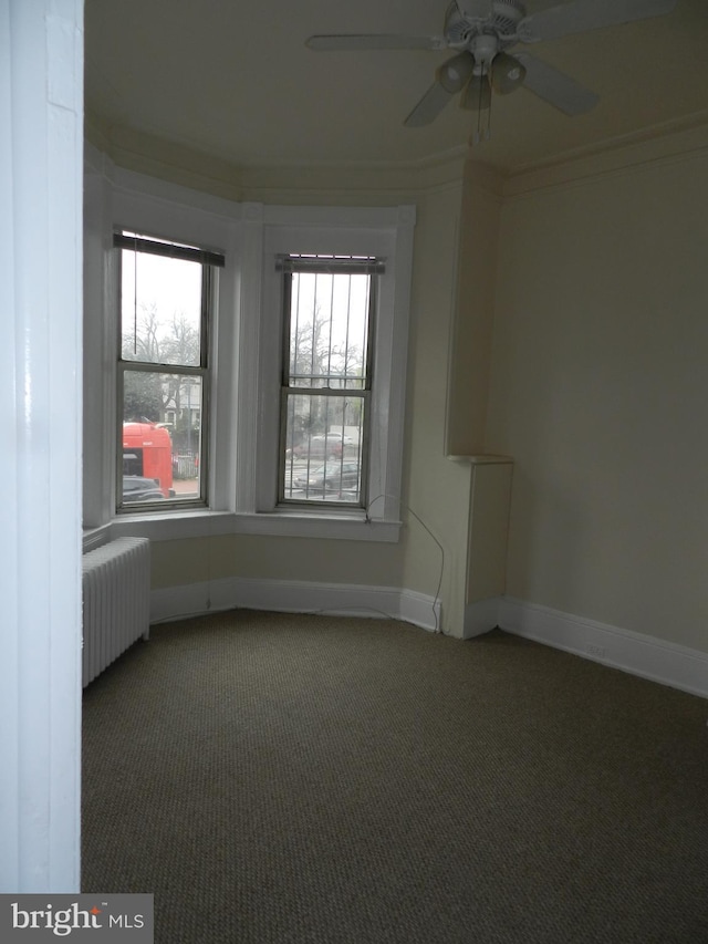 carpeted spare room with radiator heating unit, ceiling fan, and baseboards