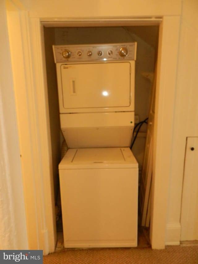 clothes washing area with stacked washing maching and dryer