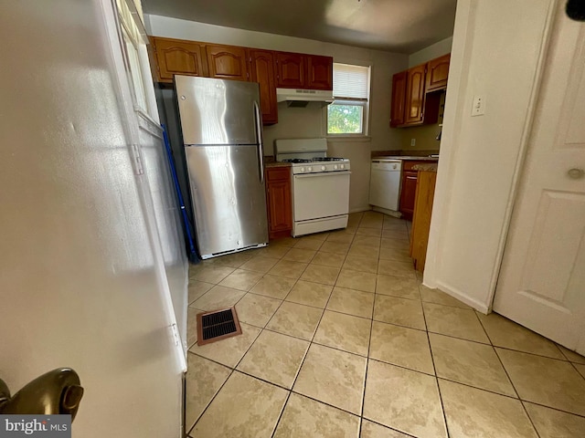 5714 63rd Ave, Riverdale, MD 20737 - kitchen featuring white appliances, under cabinet range hood, light tile patterned flooring, and light countertops