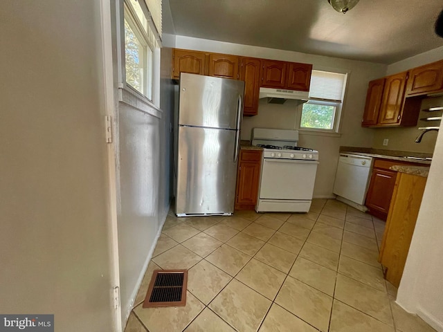 5714 63rd Ave, Riverdale, MD 20737 - kitchen with white appliances, under cabinet range hood, a sink, light tile patterned flooring, and baseboards