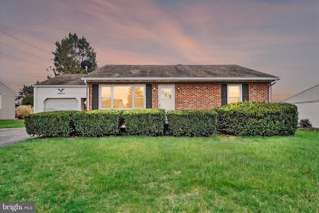 single story home with a garage, a yard, brick siding, and roof with shingles